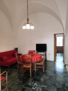 sala de estar con mesa y sofá rojo en Dimora di nonna Nina, en Galatone