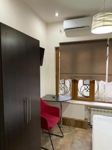 Habitación con silla roja, escritorio y ventana en Yerevan Hostel, en Ereván