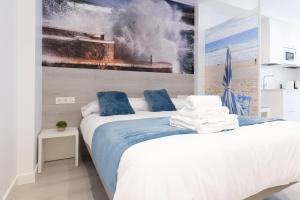 1 dormitorio con 1 cama con una pintura en la pared en Santa Marina Apartamentuak Zarautz, en Zarautz