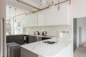 a white kitchen with a sink and a counter at Stylish Apartment in Central London - Farringdon in London
