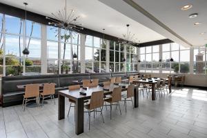 un restaurante con mesas, sillas y ventanas grandes en Holiday Inn West Covina, an IHG Hotel, en West Covina