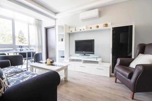 uma sala de estar com uma televisão e um sofá e cadeiras em Casa Marina Malaga em Málaga