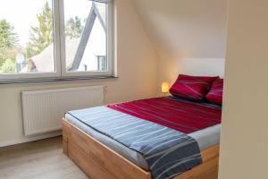 um quarto com uma cama com almofadas vermelhas e uma janela em Ferienhaus Pernice em Freest