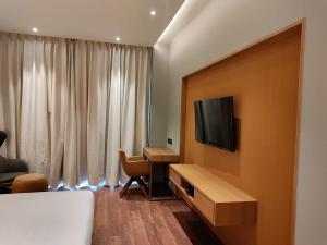 a hotel room with a desk and a television on a wall at Damson Plum in Lucknow