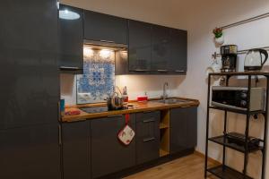 a kitchen with black cabinets and a sink and a microwave at Agora Apartments -Friend's House Sorrento in Sorrento