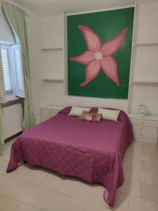 - une chambre avec un lit violet orné d'une peinture murale dans l'établissement Villa Maria, à Villanova di Ostuni