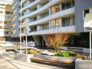 un gran edificio de apartamentos con un jardín delante de él en Departamentos Costa Nueva de Lyon, en Santiago