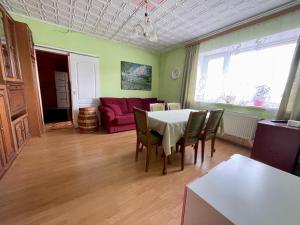 salon ze stołem i czerwoną kanapą w obiekcie Mājīgs dzīvoklis Salacgrīvā w mieście Salacgrīva