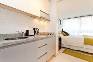 a kitchen with a white sink and white cabinets at Departamentos Costa Nueva de Lyon in Santiago