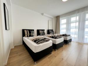 three beds in a room with white walls and wood floors at Centerapartments Premium DeLuxe in Düsseldorf +23 photos