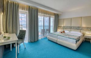 ゴールデン・サンズにあるGRIFID Metropol Hotel - Premium All inclusive & Private Beach - Adults Onlyのベッド、デスク、窓が備わるホテルルームです。