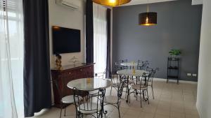 jadalnia ze stołami i krzesłami oraz telewizorem z płaskim ekranem w obiekcie Essenza del Tempo Inn w Katanii