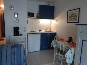 a small kitchen with blue cabinets and a table with chairs at 4RB4 Appartement type T2 bord de mer ACCES PLAGE DIRECT in Collioure
