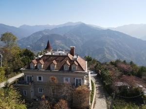 uma casa numa colina com montanhas ao fundo em Castle On A Cloud em Ren'ai