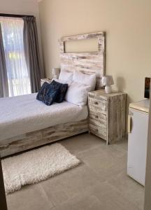 sypialnia z łóżkiem z drewnianym zagłówkiem i poduszkami w obiekcie Lime Court two w mieście Pretoria