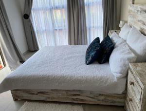 1 dormitorio con cama de madera con almohadas y ventana en Lime Court two en Pretoria