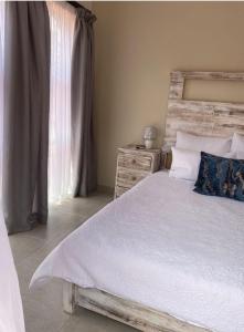 a bedroom with a bed with a wooden headboard and a window at Lime Court two in Pretoria