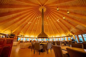 una grande sala da pranzo con un grande soffitto con tavoli e sedie di Sorrisniva Igloo Hotel ad Alta