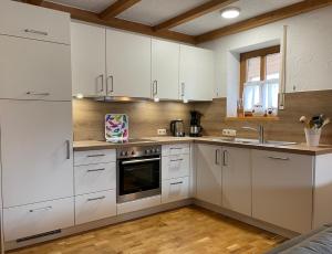 a kitchen with white cabinets and a sink at Ferienwohnungen Alpentraum - Tiefengrün und Tiefenblau in Oberstdorf