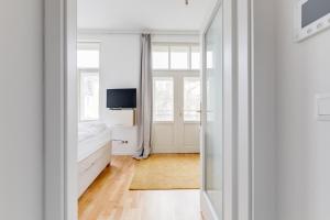 Cette chambre blanche comprend un lit et un miroir. dans l'établissement JT's Apartments Spanelska str., à Prague