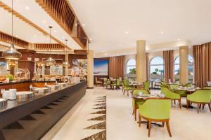 a restaurant with tables and chairs and a bar at Wyndham Garden Salalah Mirbat in Salalah