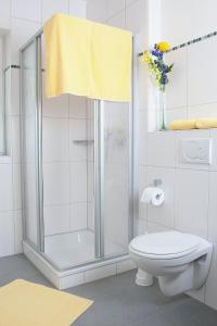 a bathroom with a shower with a toilet and a yellow towel at Gästehaus Kleeberger in Pleinfeld