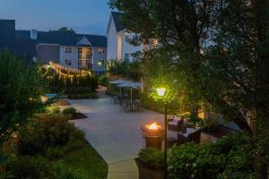 a courtyard with tables and umbrellas at night at Sonesta ES Suites Fairfax Fair Lakes in Fairfax