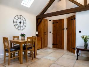 莫頓因馬什的住宿－Pass the Keys Secluded 2 bedroom cottage in scenic Aston Magna，一间带桌椅和时钟的用餐室