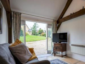 a living room with a couch and a tv and a sliding glass door at Pass the Keys Secluded 2 bedroom cottage in scenic Aston Magna in Moreton in Marsh