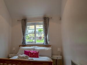a bedroom with a bed with pink pillows and a window at Pass the Keys Secluded 2 bedroom cottage in scenic Aston Magna in Moreton in Marsh