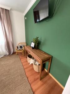 エゲルサロークにあるGólyafészek Vendégházの緑の壁にテーブルとテレビが備わる部屋