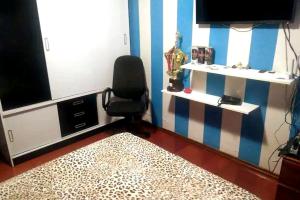 un salon avec une chaise et une télévision dans l'établissement Espaço Doméstico, à Caxias do Sul