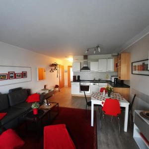 uma sala de estar com um sofá e uma mesa com cadeiras vermelhas em Ferienwohnung D1 em Graal-Müritz