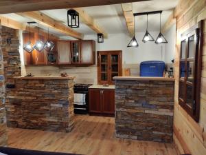 a kitchen with wooden cabinets and a stone wall at EKO KUĆA HEDONIJA in Bajina Bašta