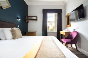 a bedroom with a large bed and a purple chair at Applewood Hotel in Bournemouth