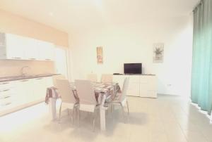 a white kitchen with a table and white chairs at Palau Fonte Vecchia apartments in Palau