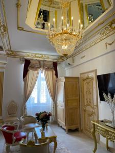 uma sala de estar com um lustre e uma mesa e cadeiras em Suite Impériale Église du Couvent em Narbona