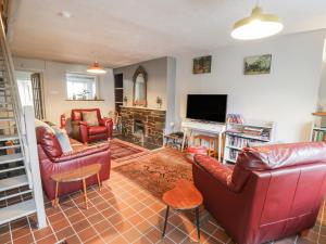 a living room with red leather furniture and a flat screen tv at 3 Alma Terrace in Llanfairfechan