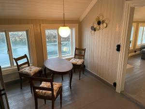 - une salle à manger avec une table, des chaises et des fenêtres dans l'établissement 2. etg i Dampskipsbrygga, Lødingen havn, à Lødingen