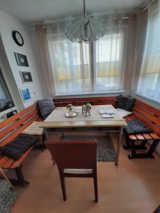 ein Esszimmer mit einem Tisch, Bänken und Fenstern in der Unterkunft Apartment Sorgenfrei in Caputh