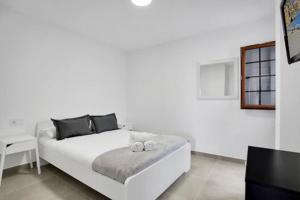 a white bedroom with a bed and a tv at Apartamento El Unicornio De Paula By Paramount Holidays in Candelaria
