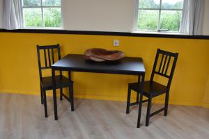 a black table and two chairs in front of a yellow wall at Happy Home-Slapen onder de sterren in Kronenberg