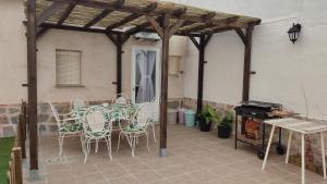 un patio con mesa, sillas y parrilla en La Casa del Cerrillo, en Sonseca
