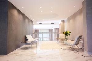 a lobby with two chairs and a table with flowers at Grand Brizo Comahue in Neuquén