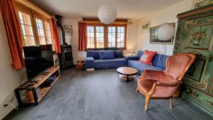 a living room with a blue couch and a tv at Snow+Surf B&B in Lauenen