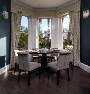 a dining room with a table and chairs and windows at Applewood Hotel in Bournemouth
