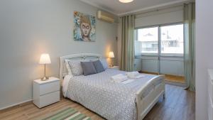 1 dormitorio con cama blanca y ventana en Comfort 1BDR Apartment W/Pool by LovelyStay, en Portimão