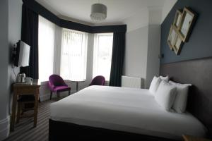 
a hotel room with a bed, chair and a window at Applewood Hotel in Bournemouth
