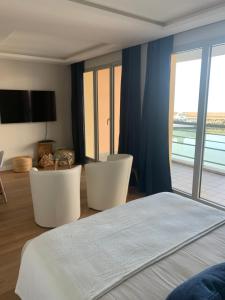 a bedroom with a bed and two chairs and a balcony at Horizon Bleu in Deauville