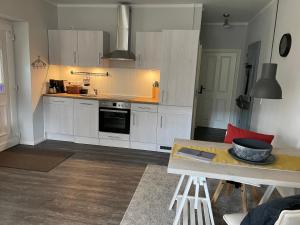 eine Küche mit weißen Schränken und einem Tisch mit einer Schüssel darauf in der Unterkunft Friesen-Lodge Ferienwohnungen in Breklum + 13 Fotos